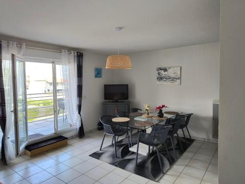 une salle à manger avec une table, des chaises et une télévision dans l'établissement Le spot, à Biscarrosse