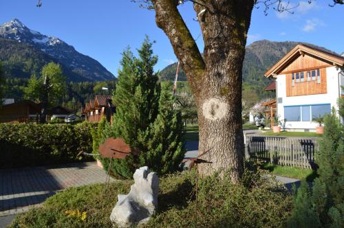 a tree in front of a house with a mountain at Alpencamp Kärnten in Kötschach