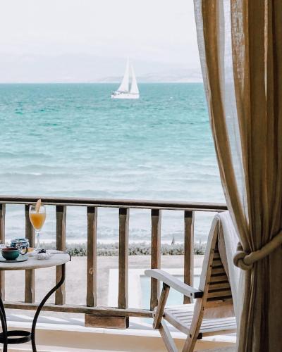 a balcony with a table and a sailboat in the ocean at Carpos Villa in Aegina Town
