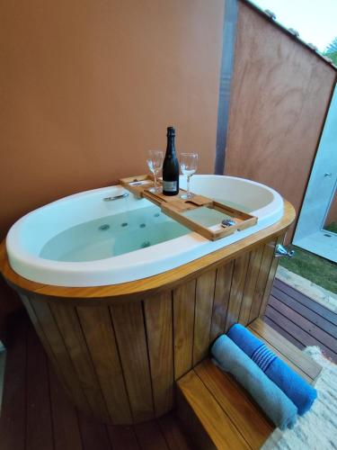 a bath tub with a bottle of wine and two glasses at Loft BeiraMar 1 in Serra