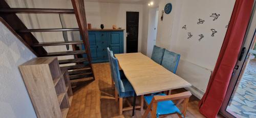 une salle à manger avec une table en bois et des chaises bleues dans l'établissement Gruissan Maison familiale 2 à 6 personnes - 3 chambres et 2 SDB !, à Gruissan