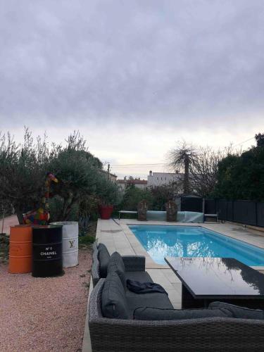 - une piscine avec un canapé et une table à côté dans l'établissement La Ciotat T2 dans villa avec piscine, à La Ciotat