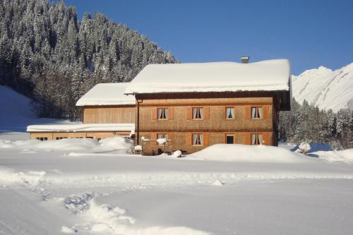 a building covered in snow in front of a mountain at Ferienbauernhof Oberhauser in Schoppernau