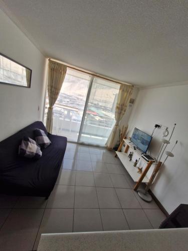 a living room with a black couch and a window at departamento pedro prado cercano al mall zofri in Iquique