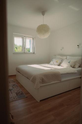 a white bed in a bedroom with a window at The Secret Garden Villa in Vela Luka
