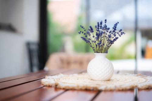a white vase with purple flowers in it on a table at Ubytování Čankovice - Domek se zahradou poblíž Chrudimi in Čankovice