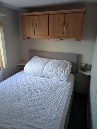 una camera da letto con letto, lenzuola bianche e armadi in legno di L28 Millfield 4 Berth 3 Bedrooms DG & GCH Familys Only And Lead Person Must Be Over 30 a Ingoldmells
