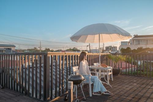 a woman sitting at a table with an umbrella at 신흥부부공간b동 in Jeju