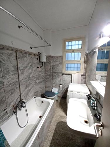 a white bathroom with a tub and a sink at Spacious Apartment 2 minutes from Omonoia Metro in Athens