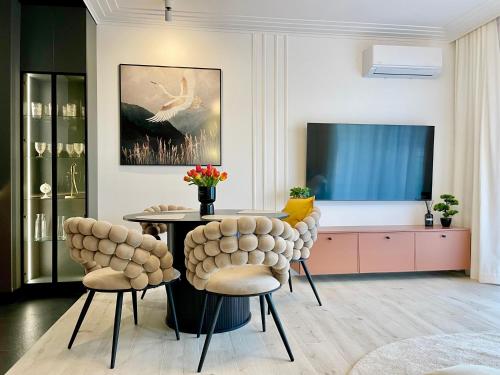 a living room with a table and chairs and a tv at Apartament ŻURAW z widokiem na jezioro Drwęckie ROYAL APARTS OSTRÓDA in Ostróda