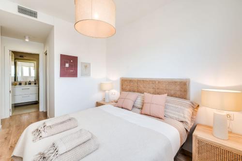 a bedroom with a large white bed with two lamps at Sky Urban Tower in Málaga