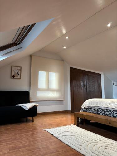 a bedroom with a bed and a couch and a window at O Lar do Canteiro in O Casal Pontevedra
