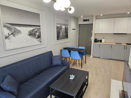 salon z niebieską kanapą i stołem w obiekcie Apartament przy plaży w mieście Niechorze