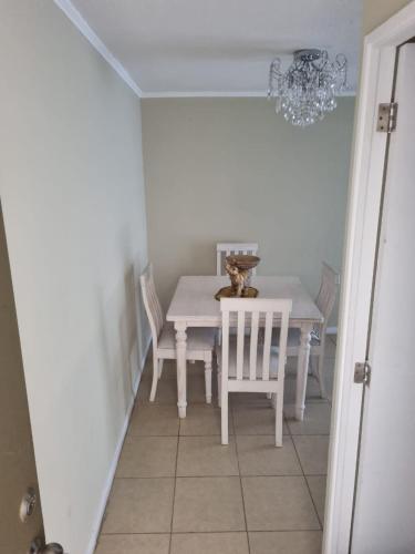 a dining room with a white table and a chandelier at Departamento acogedor in Viña del Mar