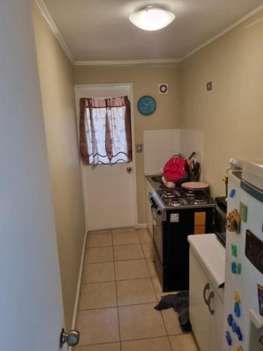 a kitchen with a stove and a door and a refrigerator at Departamento acogedor in Viña del Mar