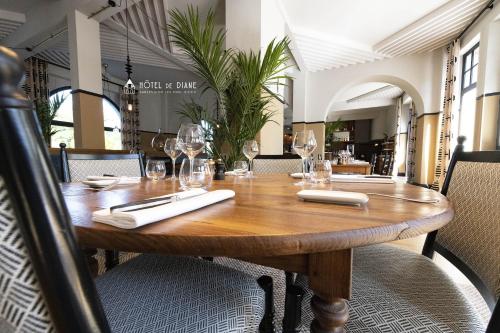 a wooden table in a restaurant with wine glasses at Hotel De Diane in Sables-dʼOr-les-Pins