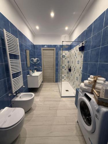 a blue tiled bathroom with a washing machine in it at Le Pupatelle Apartment in Castellammare di Stabia