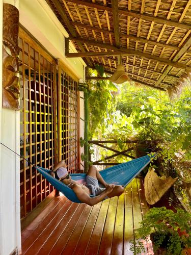 a man laying in a hammock on a porch at Appartement ATIALA in Hell-Ville