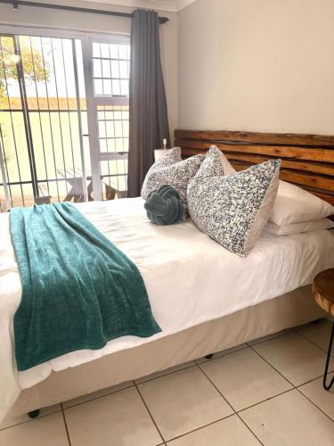 a bed with pillows and a green blanket on it at Sea Breeze Manor - Gold unit in East London