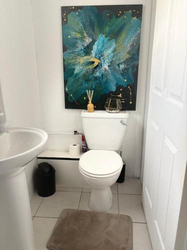 a bathroom with a toilet and a painting on the wall at Sea Breeze Manor - Gold unit in East London
