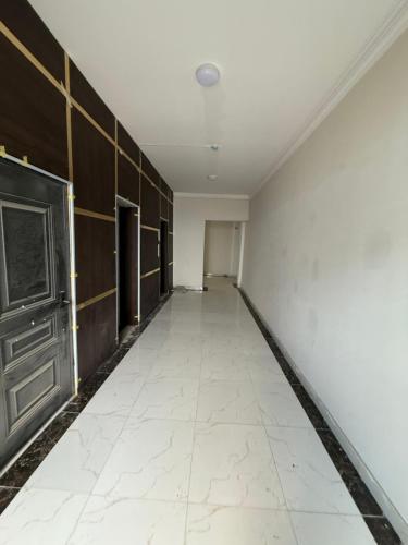 an empty hallway with a white tile floor and a ceiling at Айни60 in Dushanbe