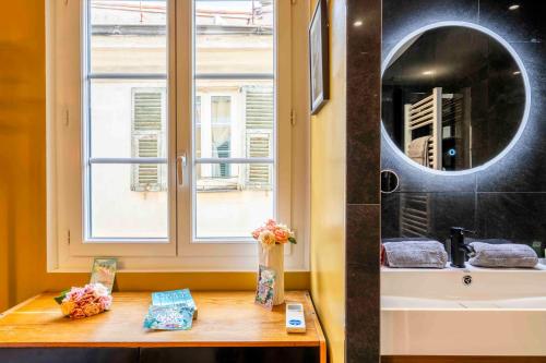 La salle de bains est pourvue d'une fenêtre et d'une table fleurie. dans l'établissement 2 chambres, balcons, vue imprenable, climatisation - PALACE BLEU, à Nice