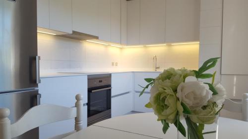 a white kitchen with a vase of flowers on a table at Centro pueblo Santa Cruz - Oleiros - A Coruña in Santa Cruz de Oleiros