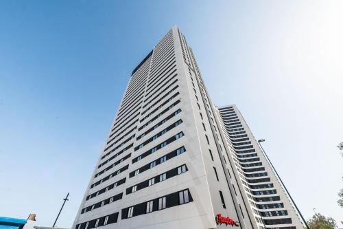 a tall white building with a blue sky in the background at Sky Urban Tower in Málaga