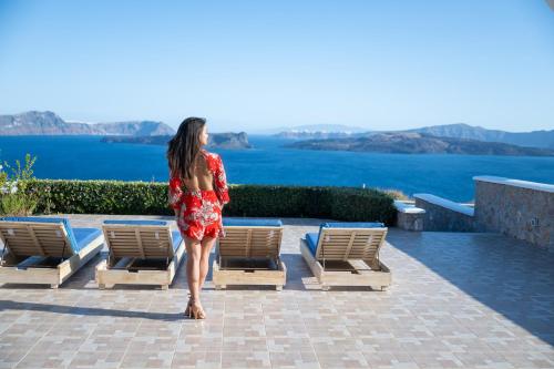 Una donna con un vestito rosso in piedi davanti alle sedie di Modus Vivendi Villas ad Akrotírion