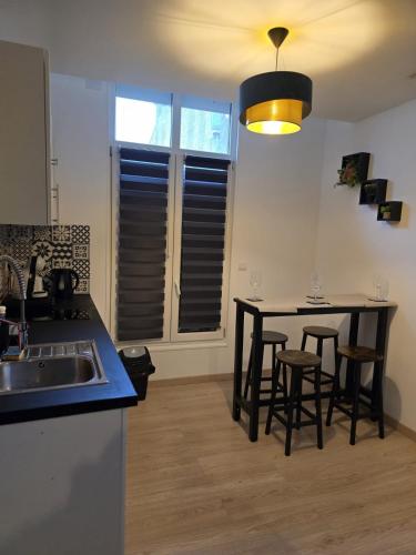- une cuisine avec un évier et une table avec des tabourets de bar dans l'établissement Hamdan Suite, à Reims