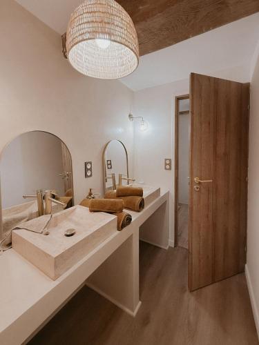 La salle de bains est pourvue d'un grand lavabo et d'un grand miroir. dans l'établissement Charmante maison en pierres, séjour à la ferme, à Saint-Georges-dʼEspéranche