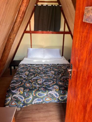 a bed in a small room with a wooden door at Pousada e Camping Tio Wil in Extrema