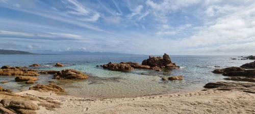una playa con algunas rocas en el agua en Maison accès direct plage corse du sud, en Coti-Chiavari