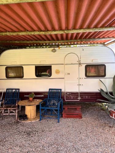 two chairs and a table in front of a trailer at Pousada e Camping Tio Wil in Extrema