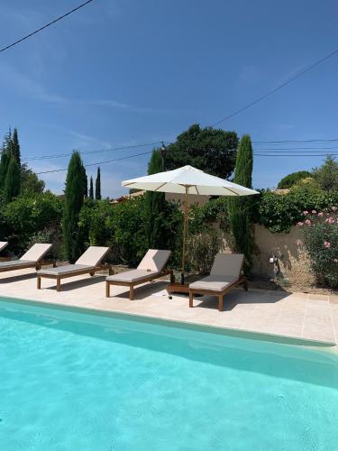 - un groupe de chaises et un parasol à côté de la piscine dans l'établissement Villa Stéphanie, à Saint-Martin-de-la-Brasque