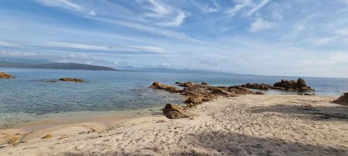 une plage de sable avec des rochers dans l'eau dans l'établissement Maison accès direct plage corse du sud, à Coti-Chiavari