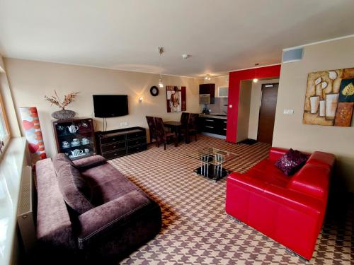 a living room with a couch and a red chair at Pokój z aneksem w hotelu blisko plaży, z garażem in Kołobrzeg