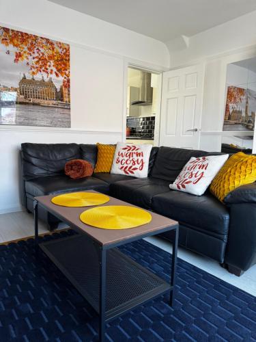 a living room with a black couch and a table at Peaceful & Convenient For business Trip & Families holiday & working proffesional-long term deals available , M1 J25-10Min , WI-Fi 500Mb , Netflix , Secure Huge Private garden with 6 cars parking space , Fully equiped kitchen , Few local shops near by in Nottingham