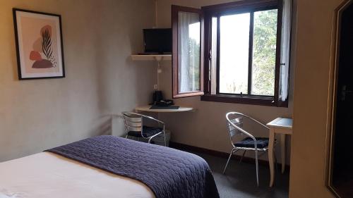 a bedroom with a bed and two chairs and a window at Relais de Frejeroques in Foissac