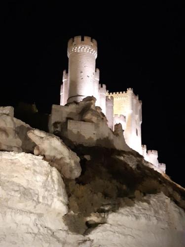 a castle sitting on top of a mountain at night at ALMA de la RIBERA in Peñafiel