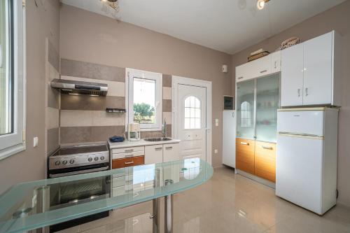 a kitchen with a glass counter top and a refrigerator at Villa Sorina Kefalonia in Svoronata