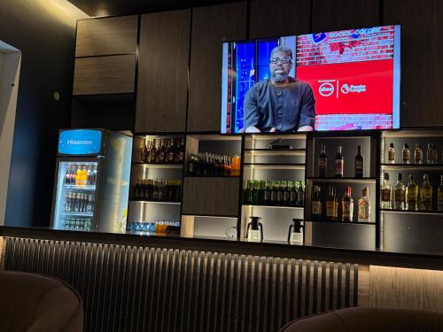 a bar with a tv behind a counter with alcohol at Ashleys Hotel in Kampala