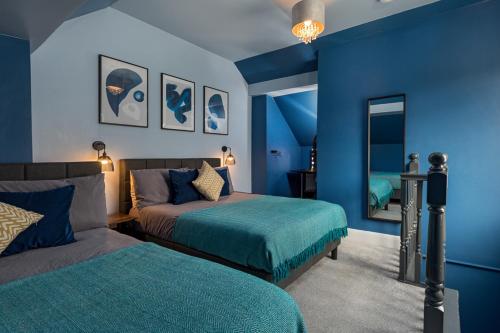 a blue bedroom with two beds and a mirror at Modern Cozy Retreat-Family-Friendly-Near City & Peak District in Sheffield