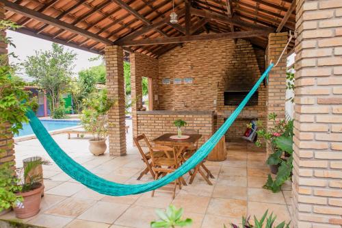 a hammock on a patio with a table and a pool at Pousada Gincoara in Jijoca de Jericoacoara