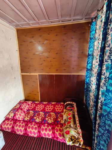 a small bed in a room with wooden walls at Shivaay homestay,cafe in Tosh