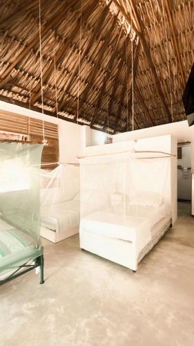 two white beds in a room with a ceiling at la casablanca moñitos in Moñitos