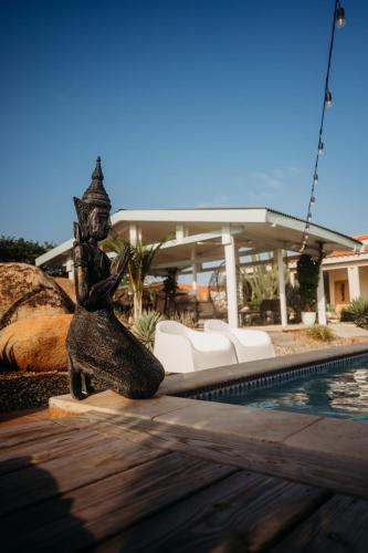 a statue of a woman sitting next to a swimming pool at Pura Vida Aruba appartement Cama in Noord
