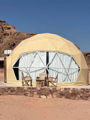 a dome tent with chairs in it in the desert at Nara Wadi RUM Camp in Wadi Rum