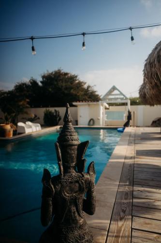 a statue sitting next to a swimming pool at Pura Vida Aruba appartement Cama in Noord
