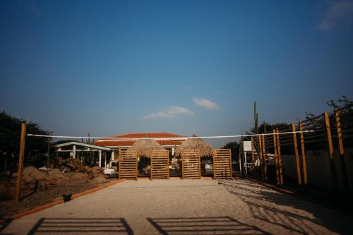 a building with straw wicker chairs and a fence at Pura Vida Aruba appartement Cama in Noord